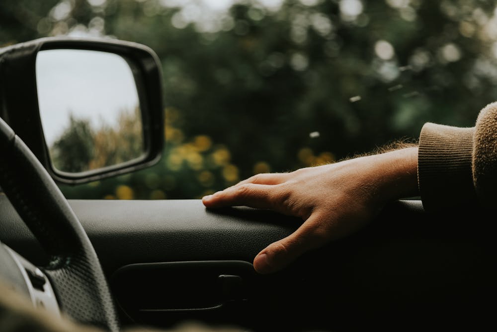 Car hacks - A person driving a car with hand on the car door.